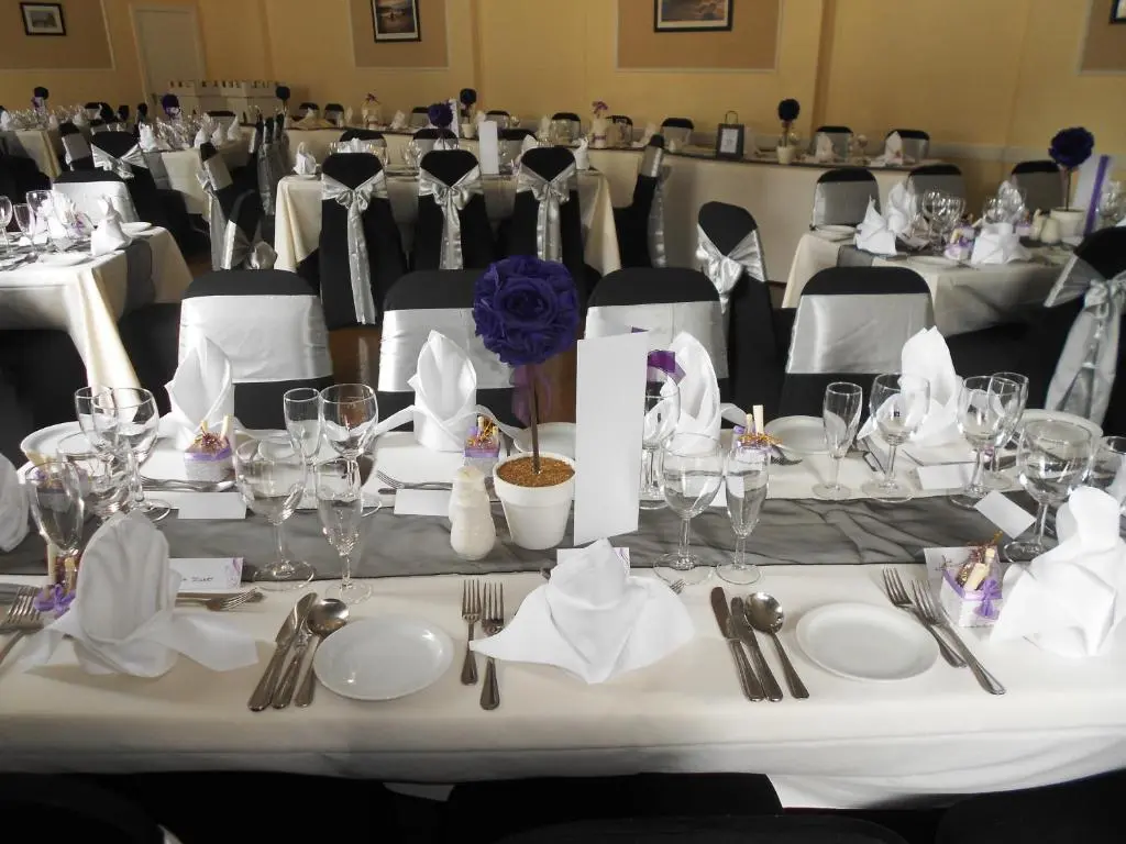 a table set up for a banquet with white plates and silverware at The Royal Hotel Tain in Tain