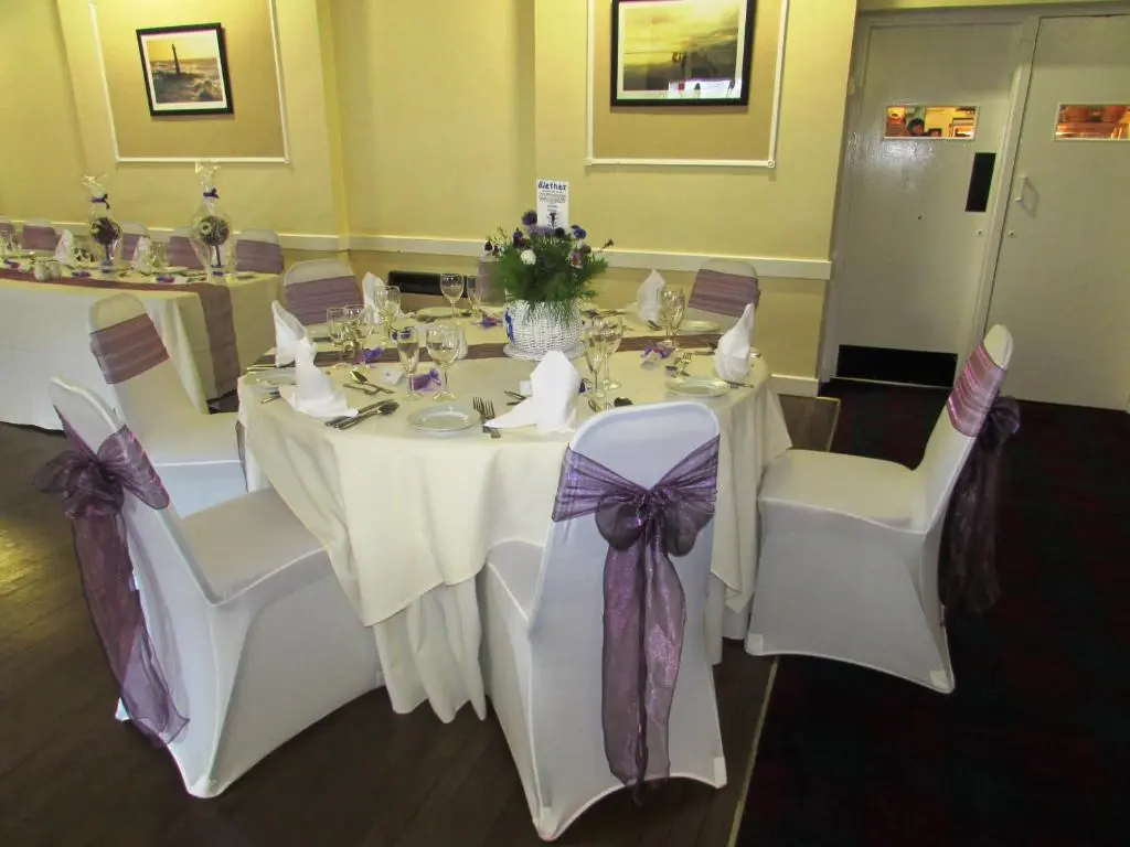 a dining room with a table and chairs with purple bows at The Royal Hotel Tain in Tain