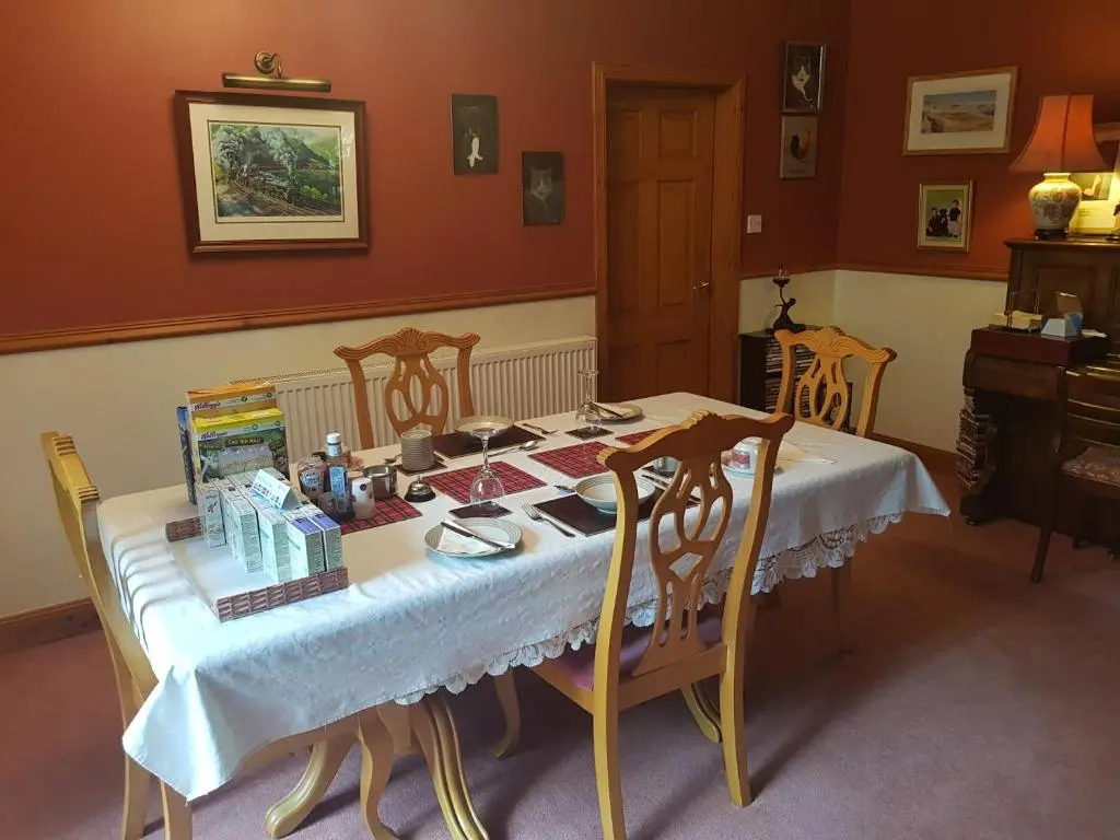 a dining room with a table with chairs and a piano at Hosefield Bed and Breakfast in Ellon