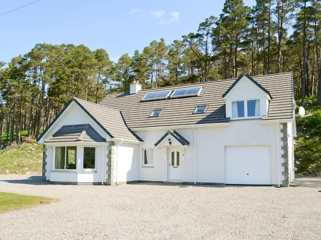 a large white house with a garage at March Cottage in Glenrossal