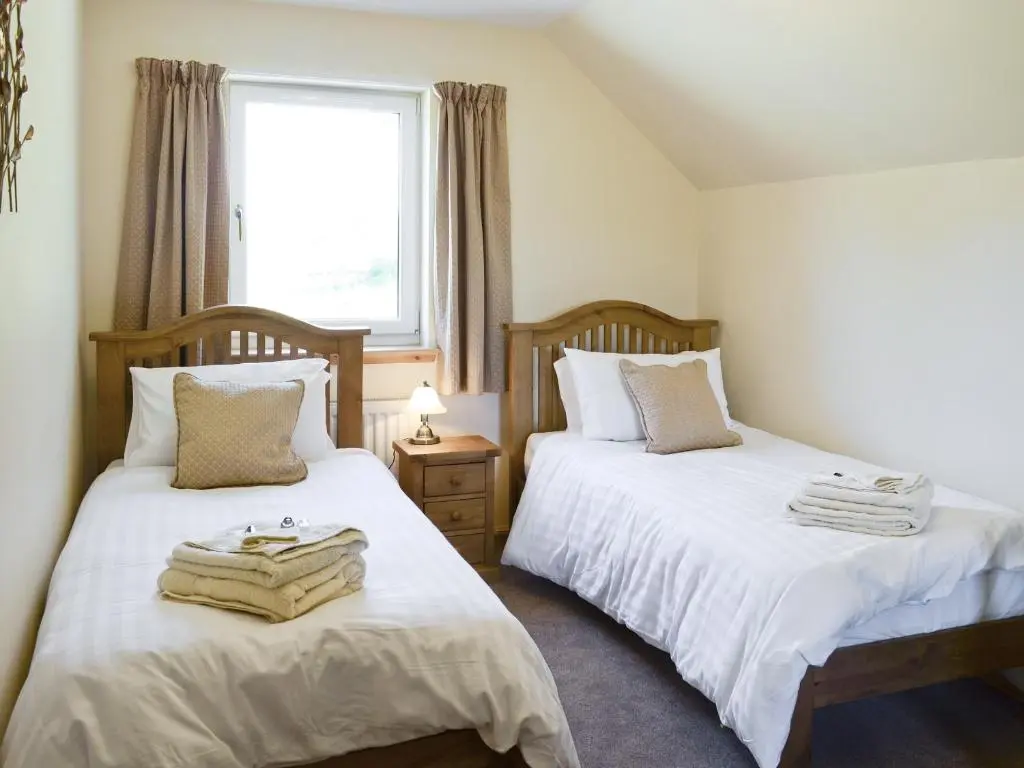 a bedroom with two beds and a window at March Cottage in Glenrossal