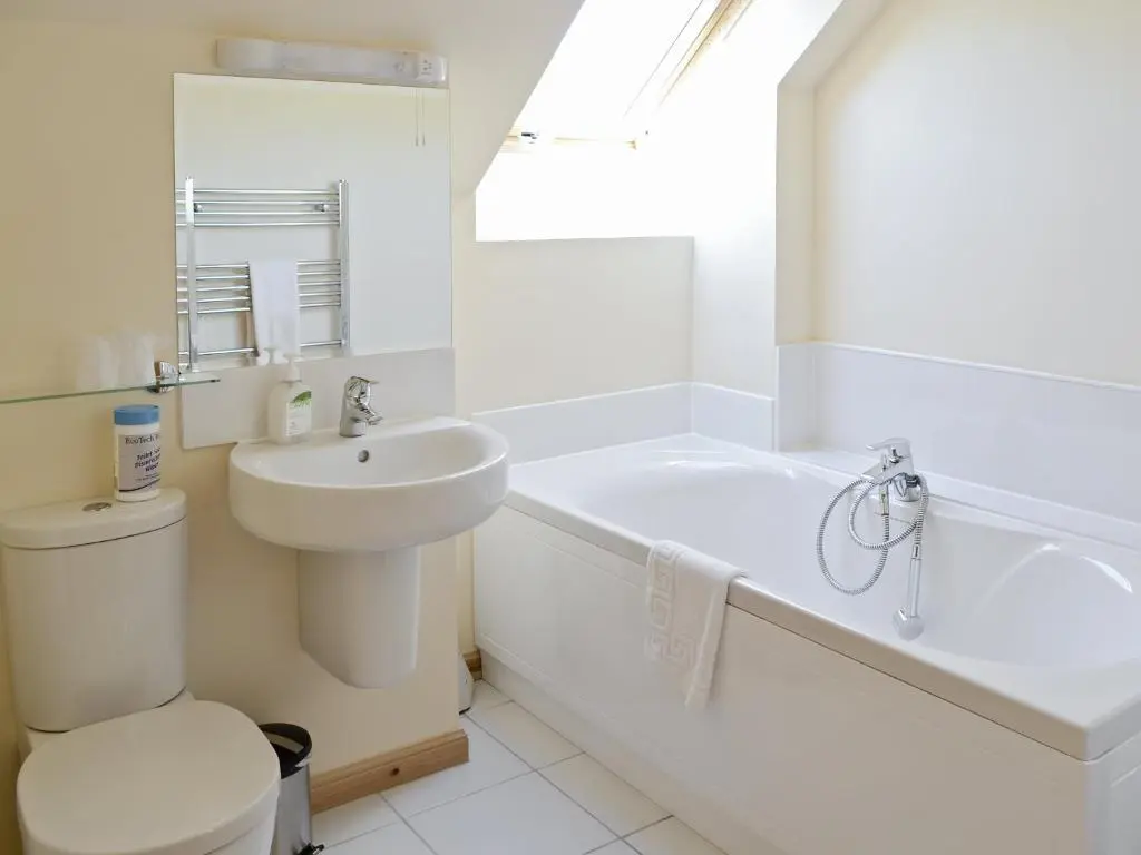 a white bathroom with a sink and a tub and a toilet at March Cottage in Glenrossal