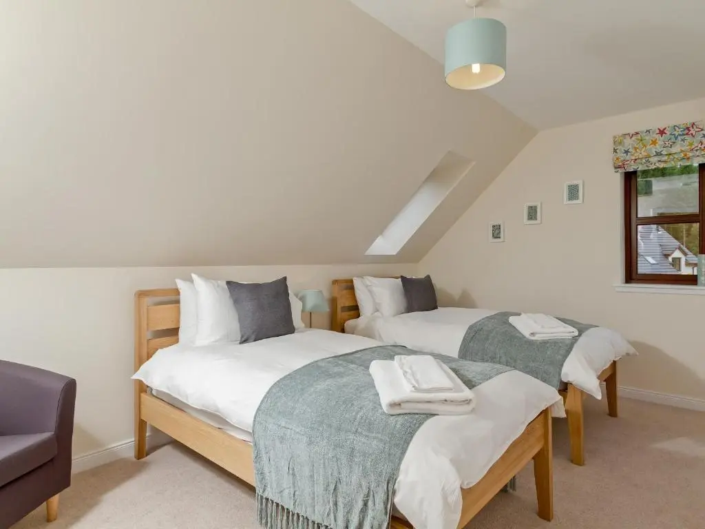 a bedroom with two beds with towels on them at Birch Corner in Aviemore