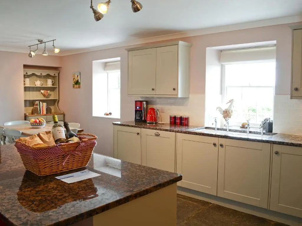 a kitchen with white cabinets and a basket on a counter at Drummuie House in Golspie