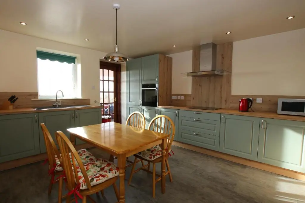 a kitchen with a wooden table and chairs at Taigh An Clachair in Lybster
