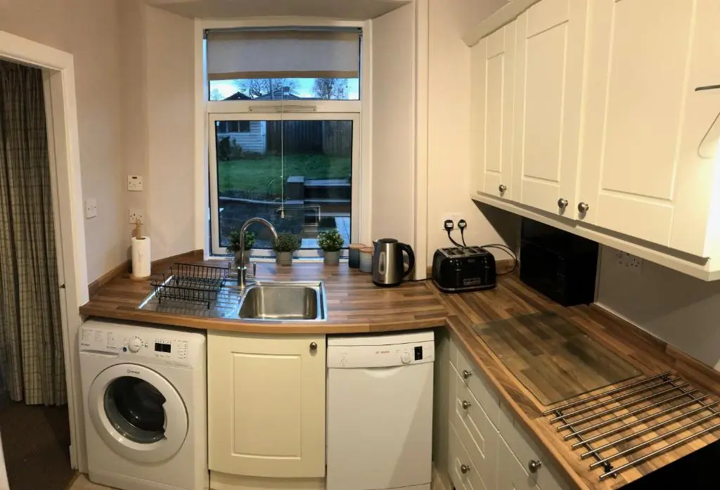 a kitchen with a sink and a washing machine at Carrick House in Kingussie