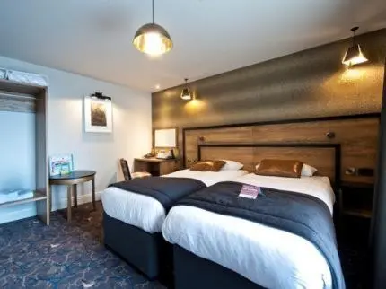 a hotel room with two beds and a desk at The Saltoun Inn in Fraserburgh