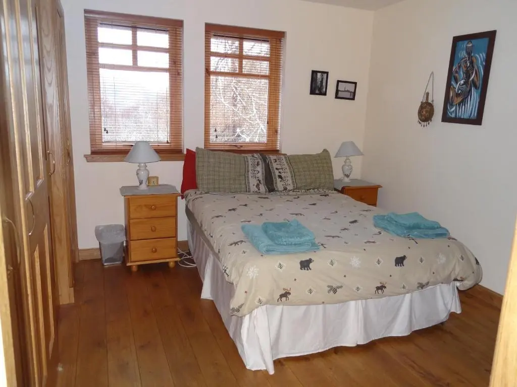 a bedroom with a bed and two windows at Dullatur in Newtonmore