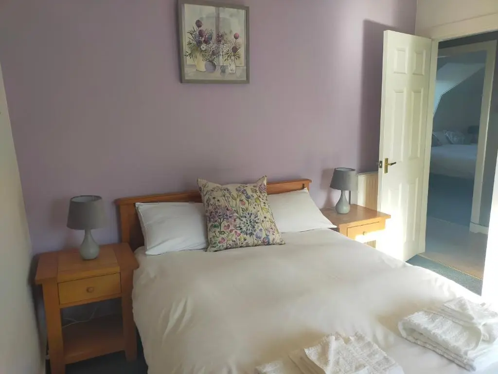 a bedroom with a white bed with two tables and two lamps at The Loft, Inverness in Inverness