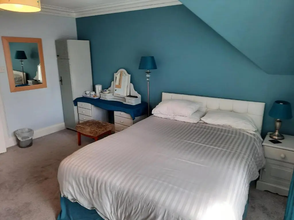 a bedroom with a white bed and a blue wall at Jacobite Rose in Inverness