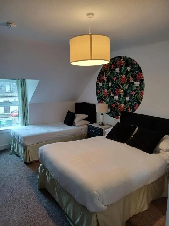 a hotel room with two beds and a chandelier at Jacobite Rose in Inverness