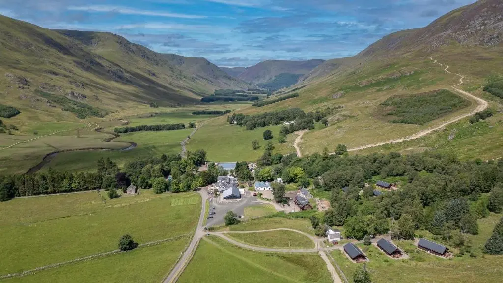 an aerial view of a farm in the mountains at Glen Clova Hotel & Luxury Lodges in Millton of Clova