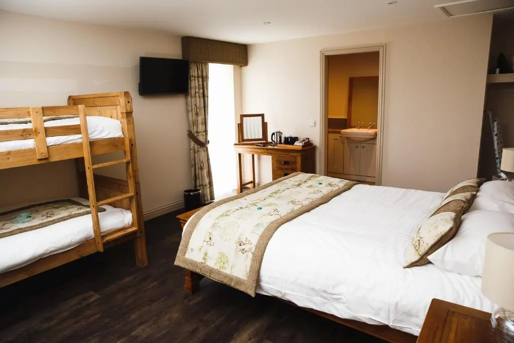 a bedroom with two bunk beds and a bathroom at Glen Clova Hotel & Luxury Lodges in Millton of Clova
