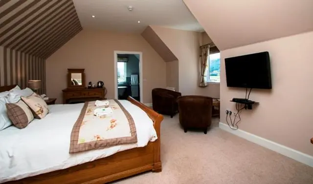 a bedroom with a bed and a flat screen tv at Glen Clova Hotel & Luxury Lodges in Millton of Clova
