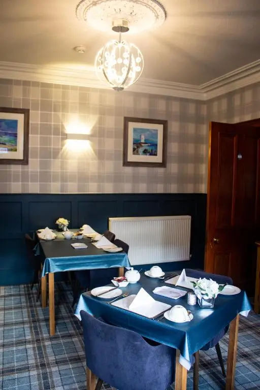 a dining room with two tables and a chandelier at Kintrae B&B in Buckie