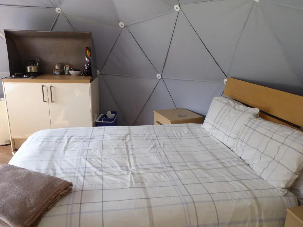a bedroom with a large bed with a gray wall at Inver Coille Campsite in Fort Augustus
