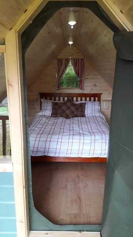 a bed in the middle of a room in a cabin at Inver Coille Campsite in Fort Augustus