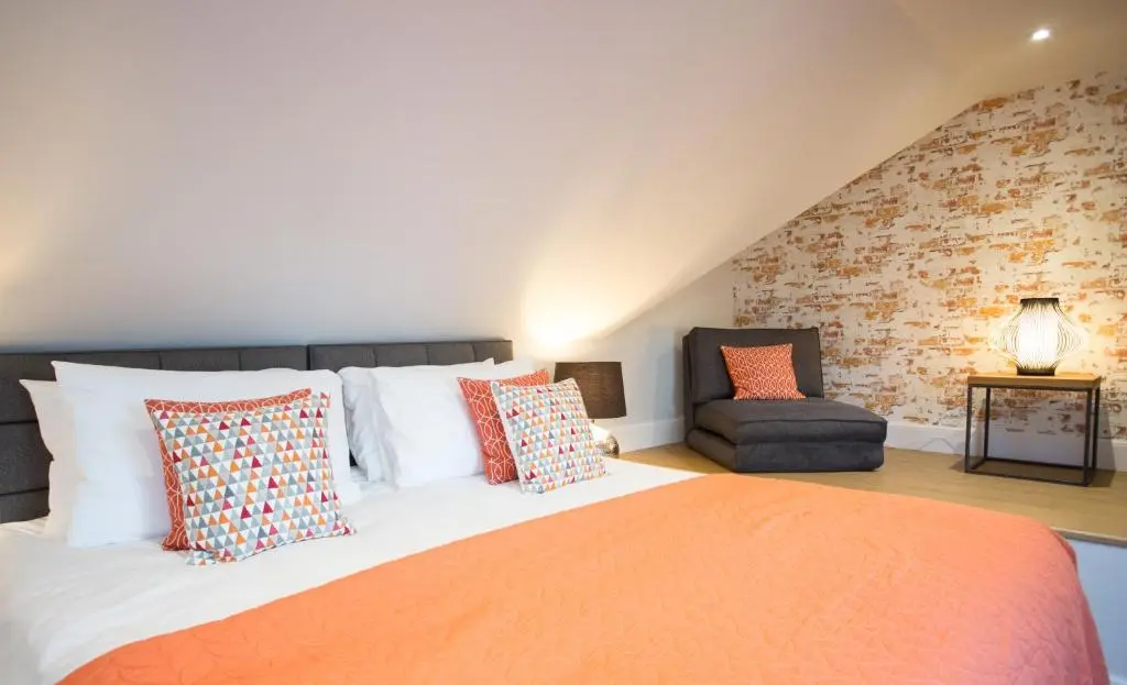 a bedroom with a large bed and a chair at Glenmoriston Town House Apartments in Inverness