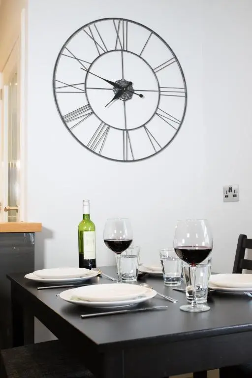 a table with glasses of wine and a clock on the wall at Glenmoriston Town House Apartments in Inverness