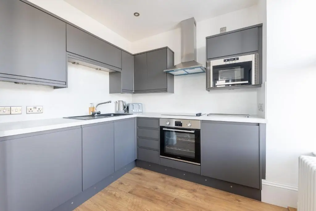 a kitchen with gray cabinets and a sink and a microwave at Glenmoriston Town House Apartments in Inverness