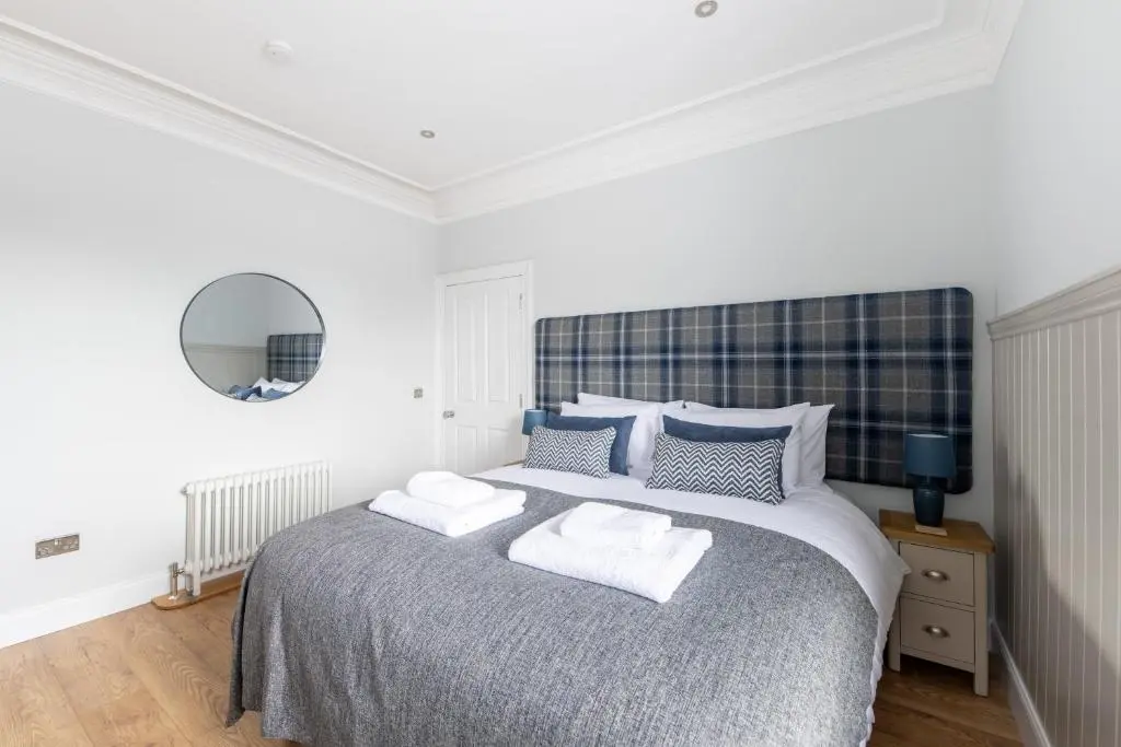 a white bedroom with a large bed with two pillows at Glenmoriston Town House Apartments in Inverness