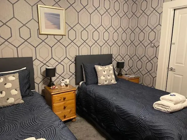 a bedroom with two beds and two night stands at Dionard Guest House in Inverness