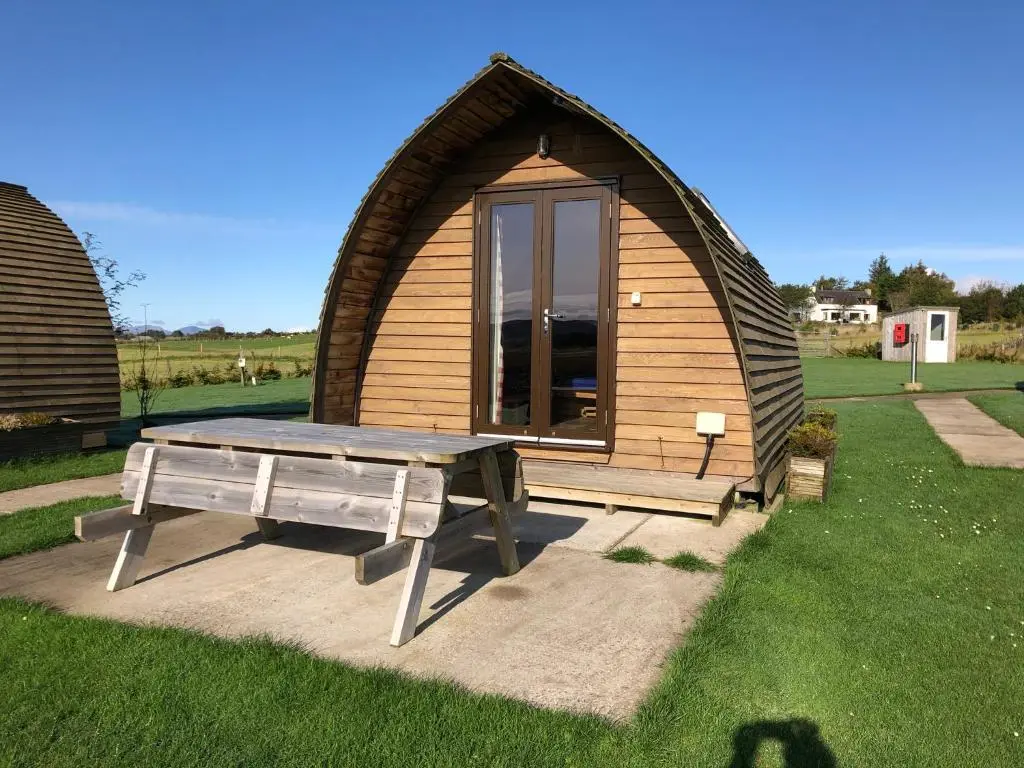 a small hut with a picnic table in front of it at Loch Shin Glamping Pods in Lairg
