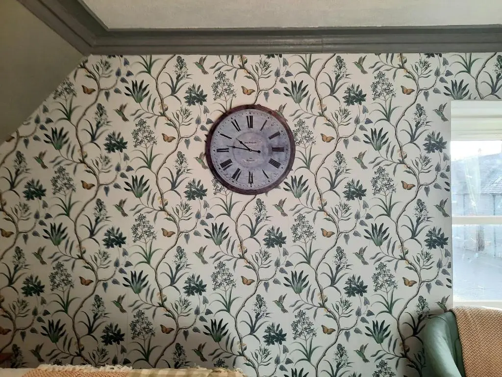 a clock on a wall with a floral wallpaper at Argyle Guest House in Tomintoul