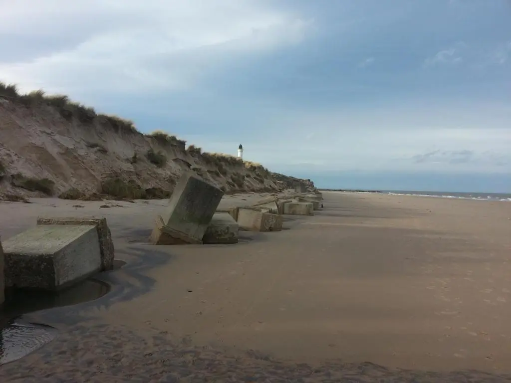 a beach with rocks on the sand and the ocean at Tighnabruaich Annex in Lossiemouth