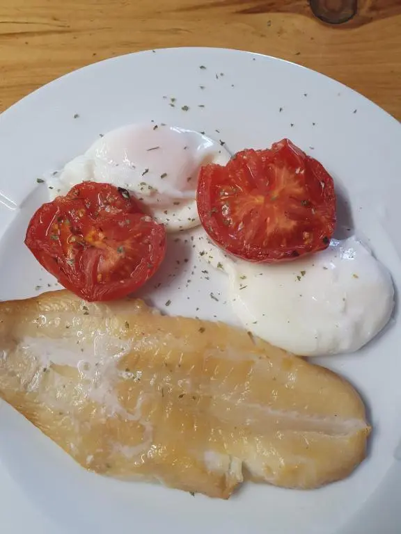 a plate of food with eggs and tomatoes on a table at St Michaels Guest House in Elgin