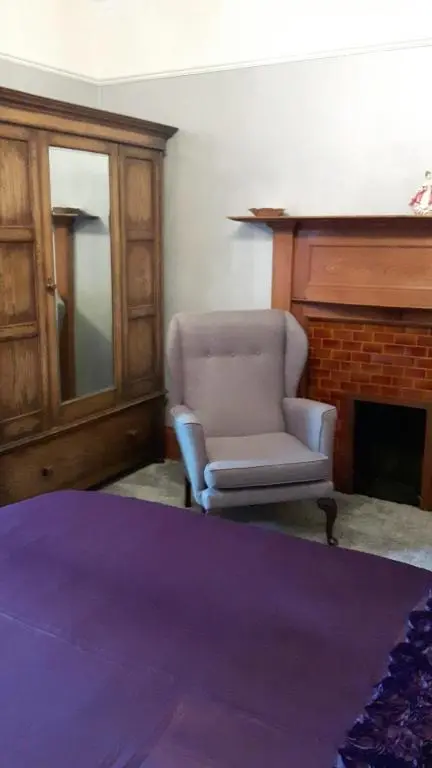 a living room with a chair and a fireplace at St Michaels Guest House in Elgin