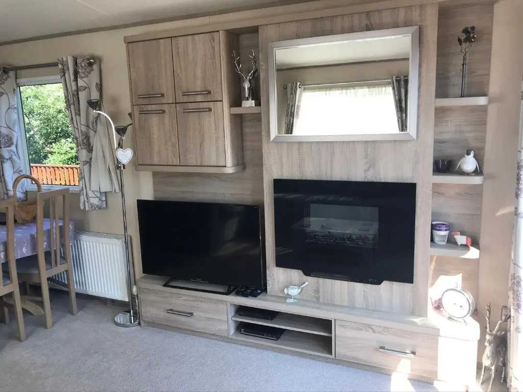 a living room with a flat screen tv and a entertainment center at Riverbank Lodge in Aviemore