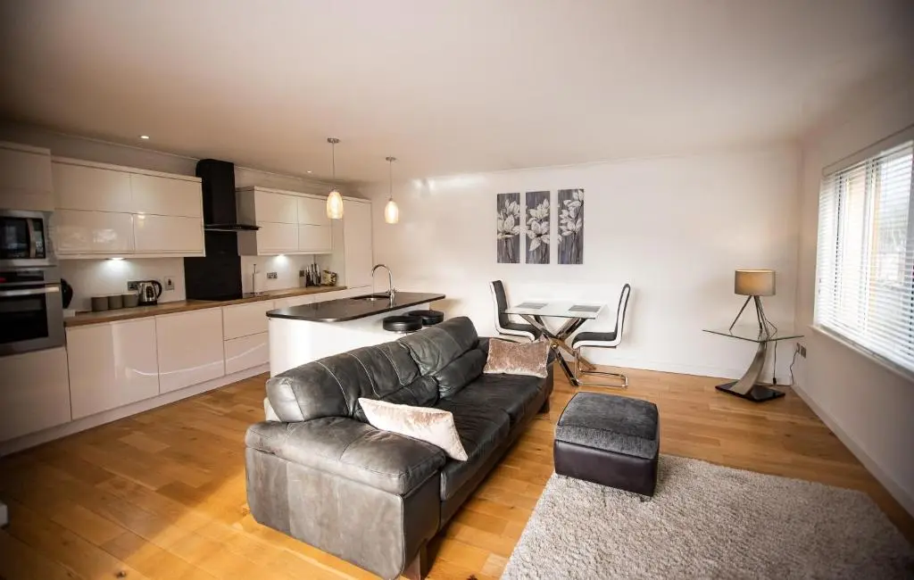 a living room with a couch and a kitchen at Langley Cottage with patio, spacious rooms - part of Langley Serviced Apartments several properties in Wick in Wick
