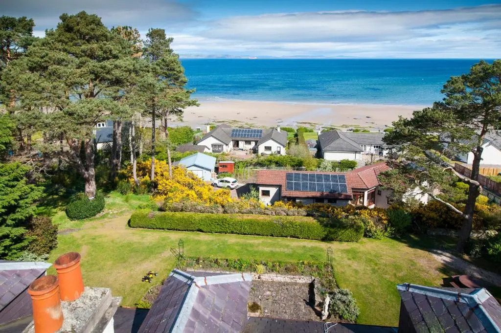 an aerial view of a house with a garden and the ocean at Invernairne in Nairn