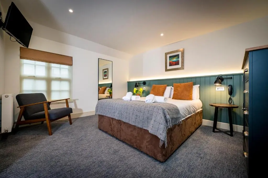 a bedroom with a bed and a chair and a television at Loch Ness Inn in Drumnadrochit