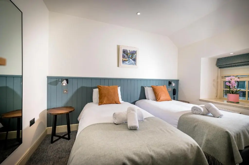 a room with three beds with towels on them at Loch Ness Inn in Drumnadrochit