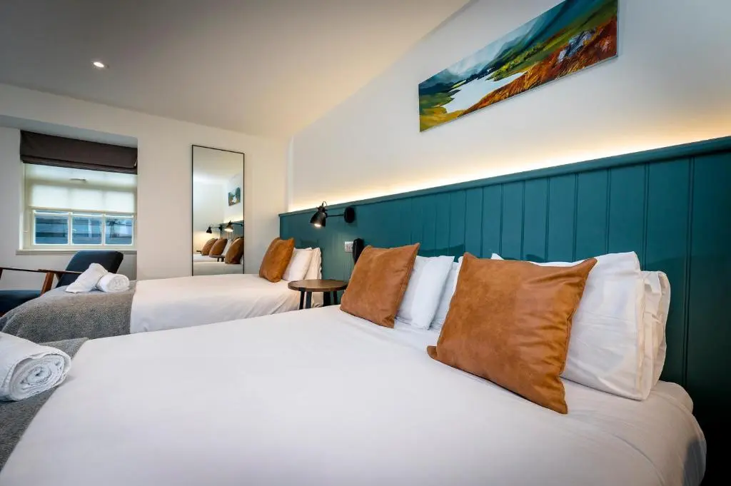 a hotel room with two beds and a blue wall at Loch Ness Inn in Drumnadrochit