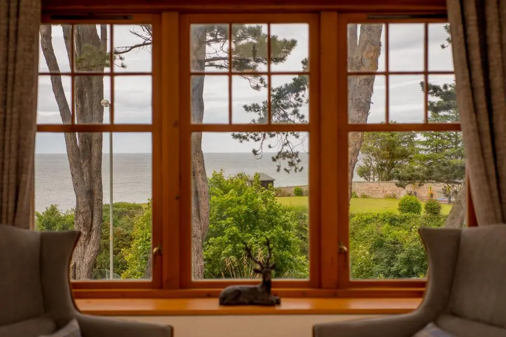 a window with a view of the ocean seen through it at Sea View Lodge in Nairn