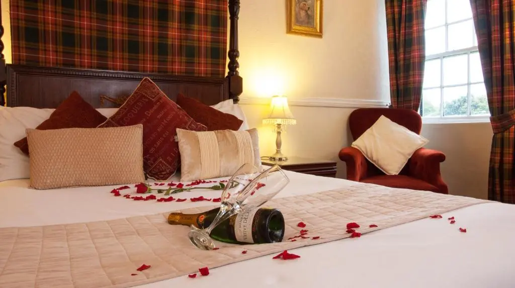 a bedroom with a bed with red rose petals on it at Glenmoriston Arms Hotel in Invermoriston