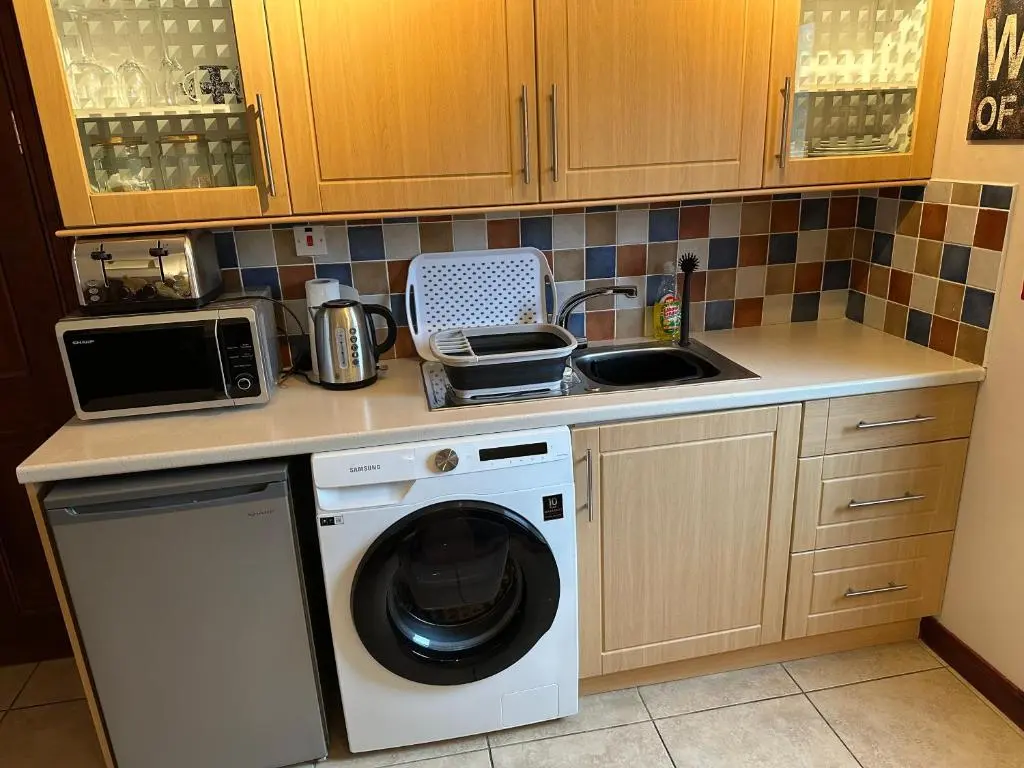 a kitchen with a washing machine and a sink at Dunhallin House in Inverness