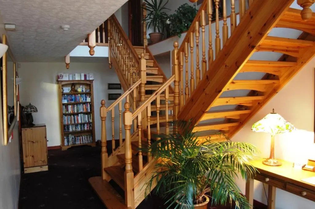 a wooden staircase in a living room with a plant at Dunhallin House in Inverness