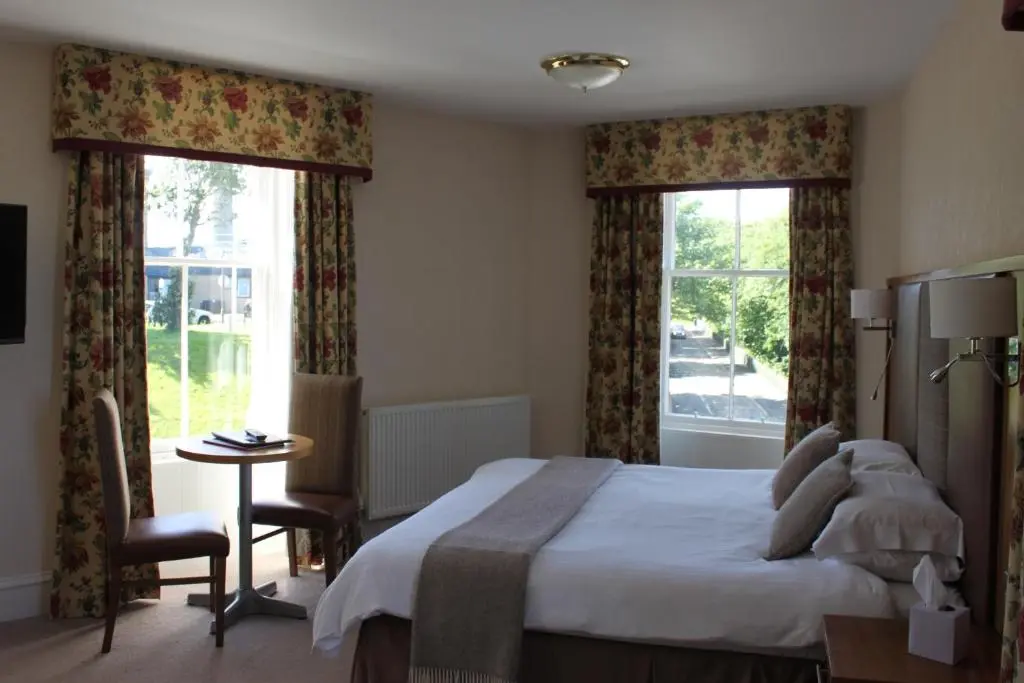 a bedroom with a large bed and two windows at Mackays Hotel in Wick