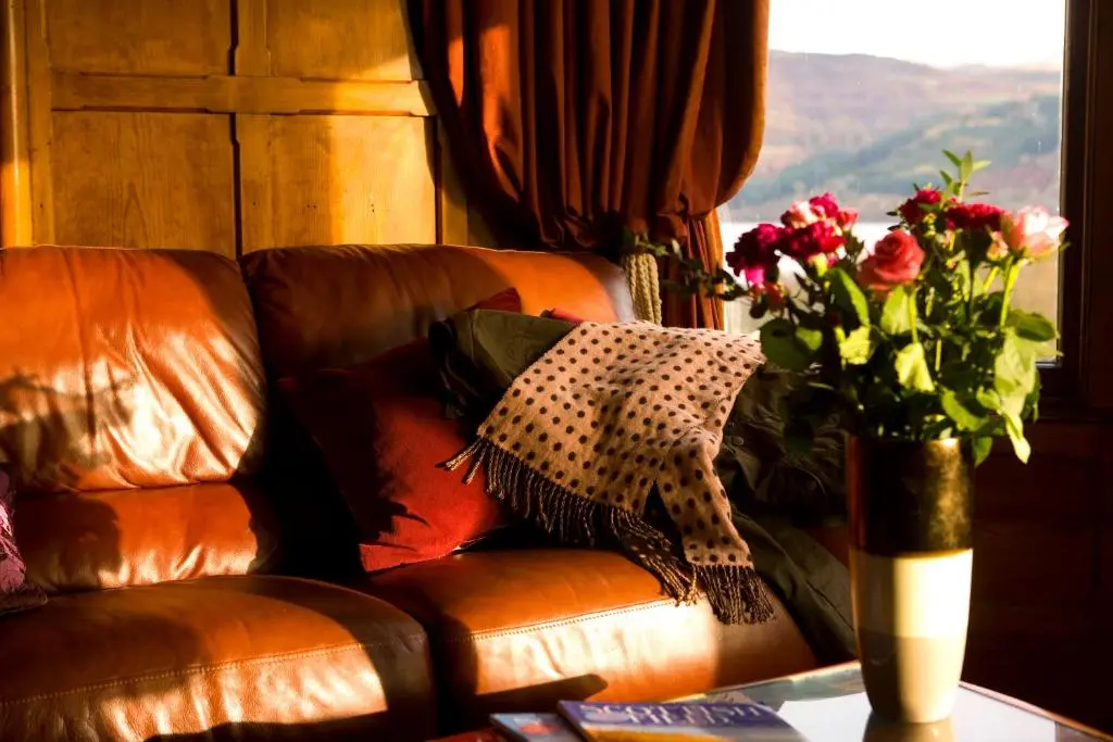 a vase of flowers on a table next to a couch at Inch Hotel in Fort Augustus