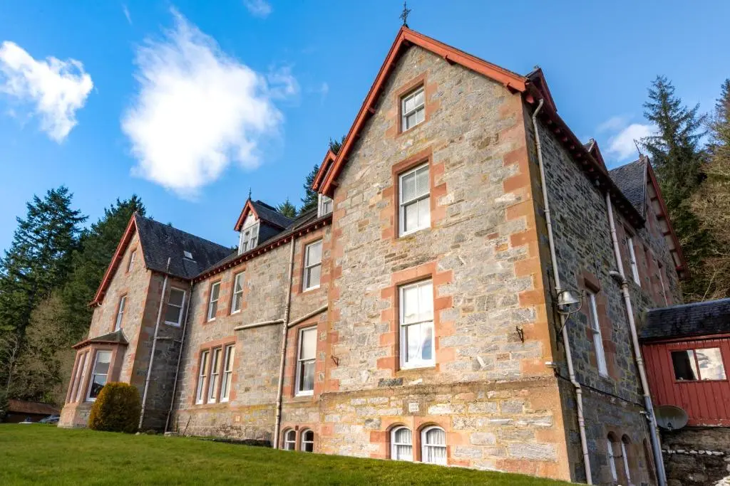 an old brick building on a green lawn at Inch Hotel in Fort Augustus