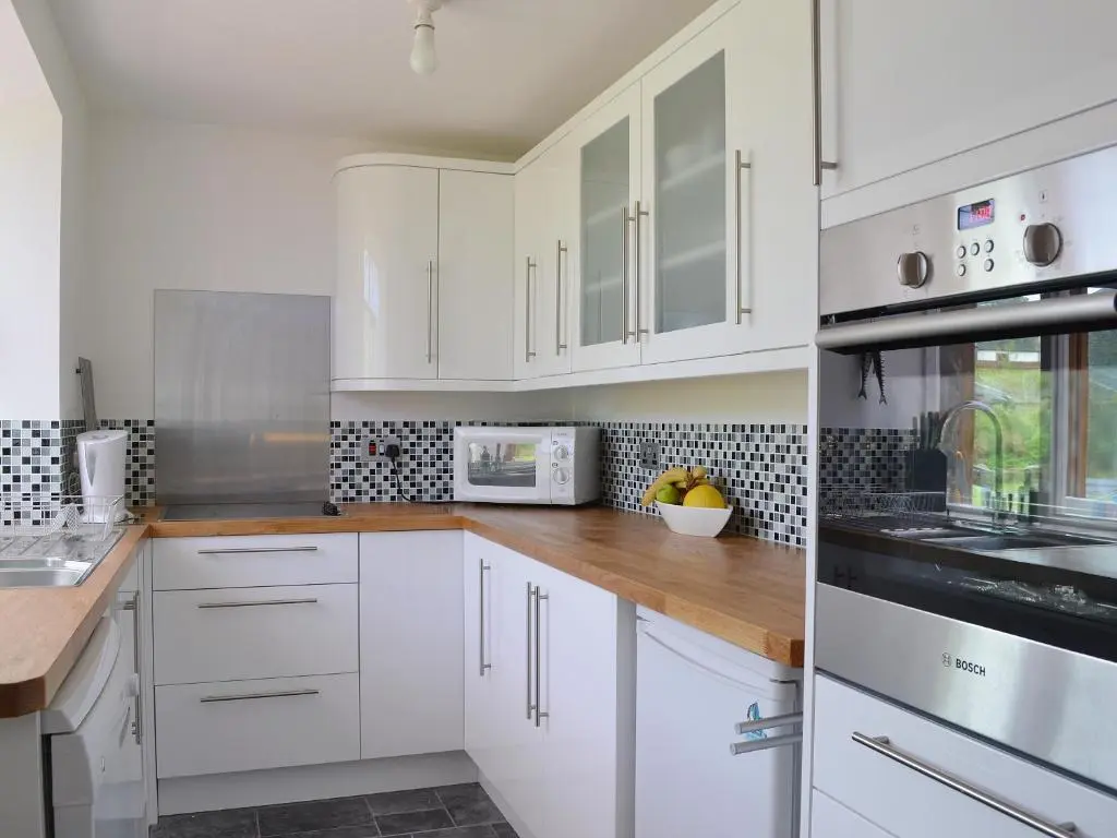 a white kitchen with white cabinets and white appliances at Sandy's Hoose in Portmahomack