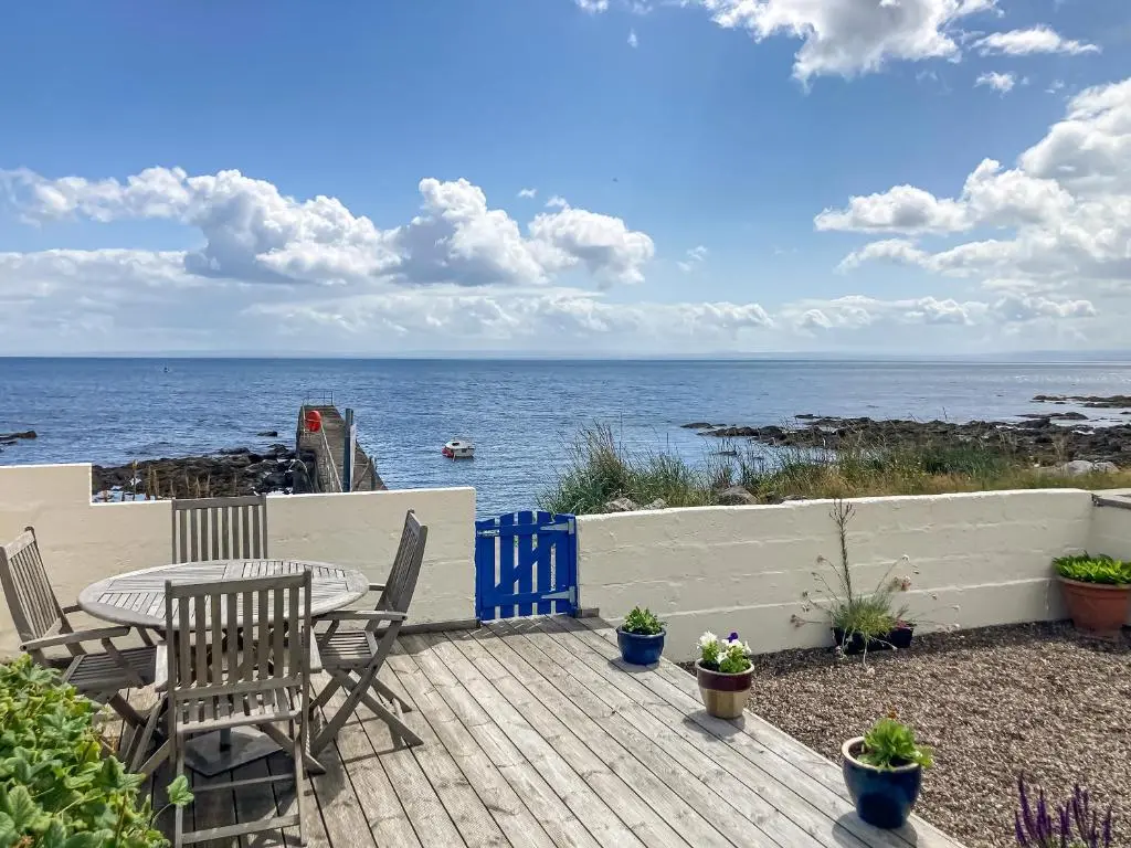 a patio with a table and chairs and the ocean at Cross Tides in Hilton of Cadboll