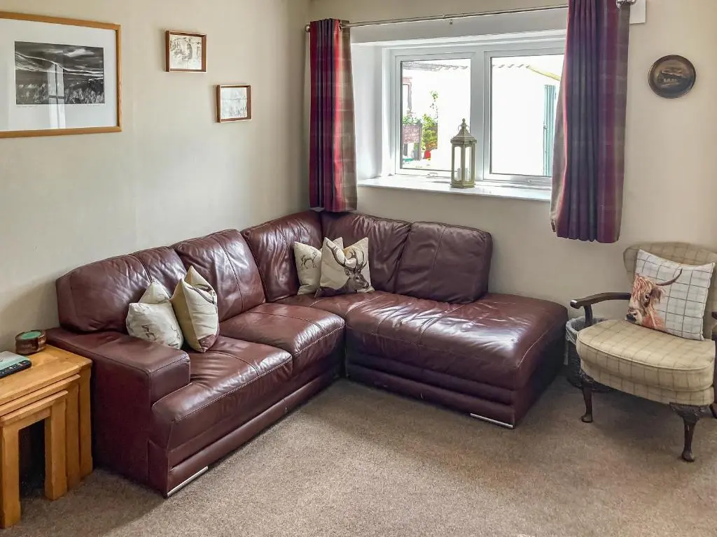 a brown leather couch in a living room with a window at Cross Tides in Hilton of Cadboll