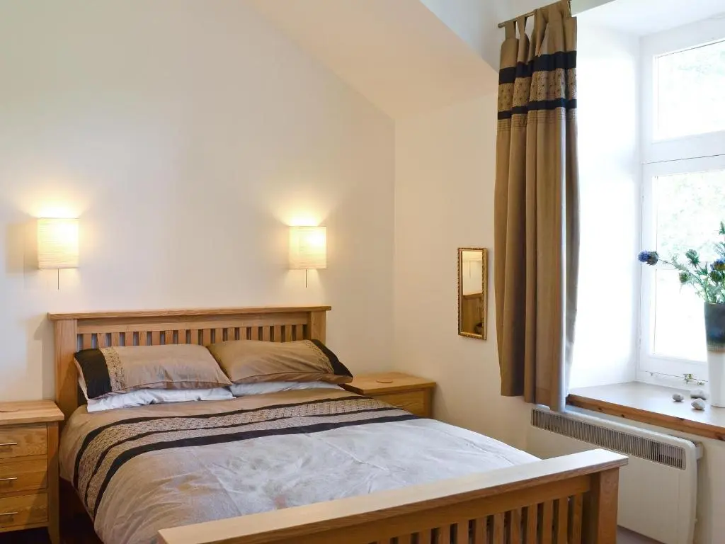 a bedroom with a bed and a window at The Old Granary in Ballindalloch
