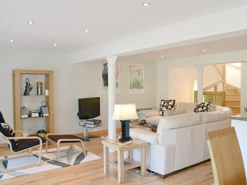 a living room with a white couch and a tv at The Old Granary in Ballindalloch