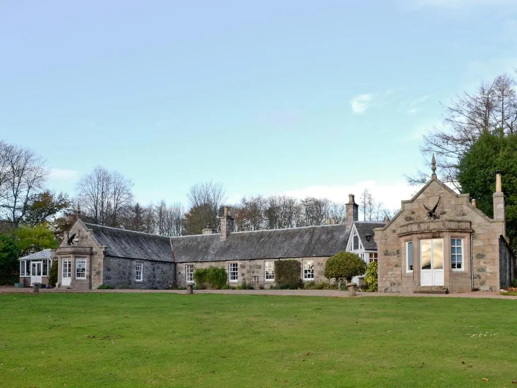 an old stone house with a green lawn at The Mews in Insch